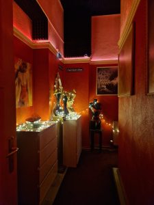 Stimmungsvolle Raumdekoration im roten Stil mit Kunstwerken und Beleuchtung.