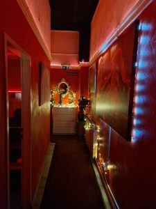 Innenaufnahme mit roter Wandfarbe, dekorativen Lampen und künstlerischen Akzenten im Noble Atlas.